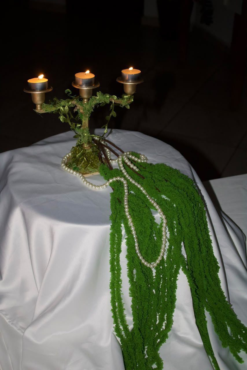 Candelabro de latão com amaranto verde sobre linho branco