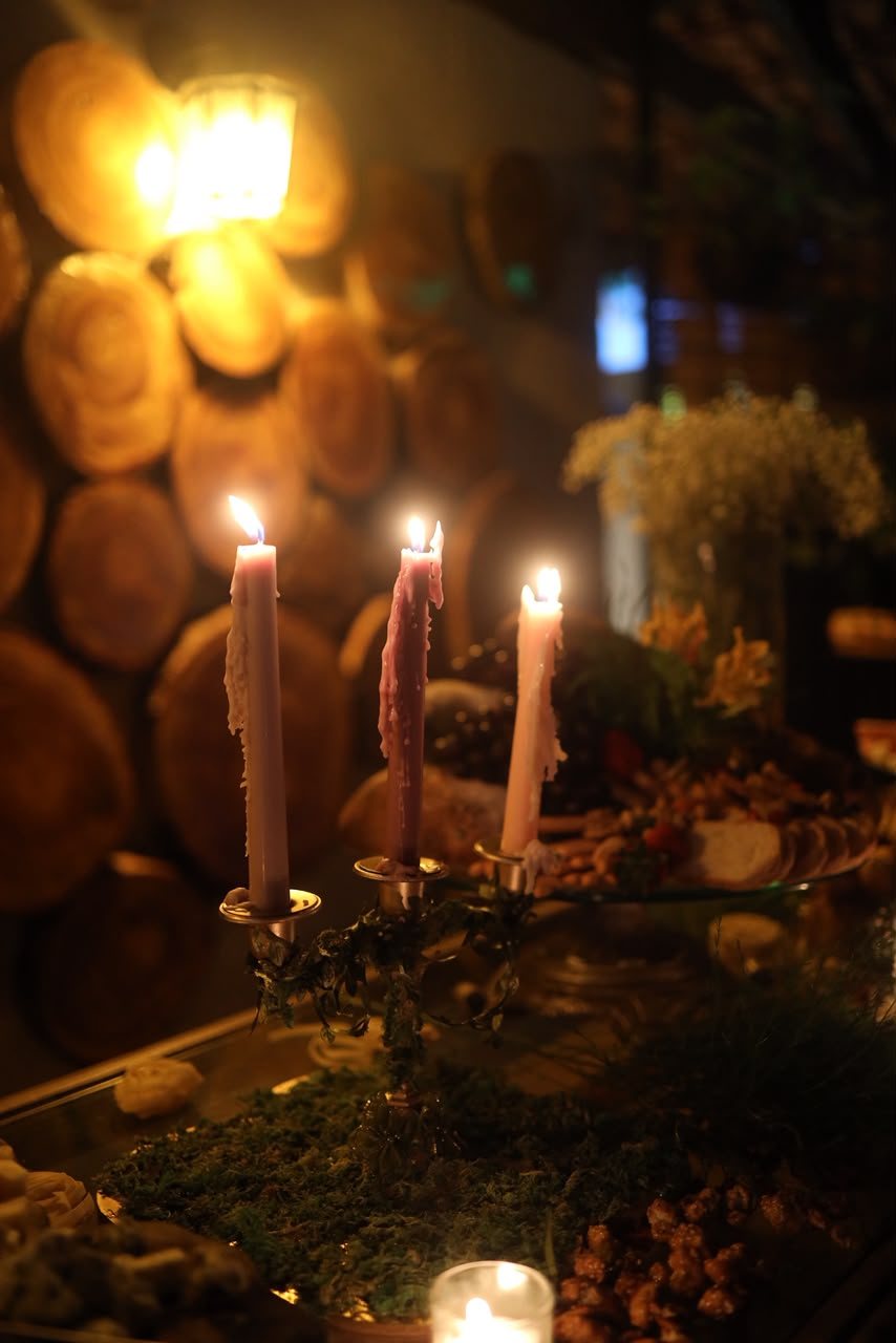 Velas sobre parede de lenha — Candelabro com velas em tons terrosos apoiado em muro de lenha, ao ar livre.